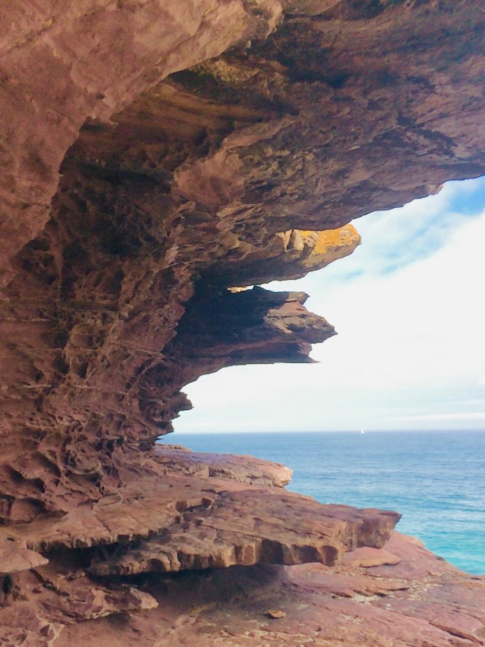 A red sandstone overhang framing the ocean