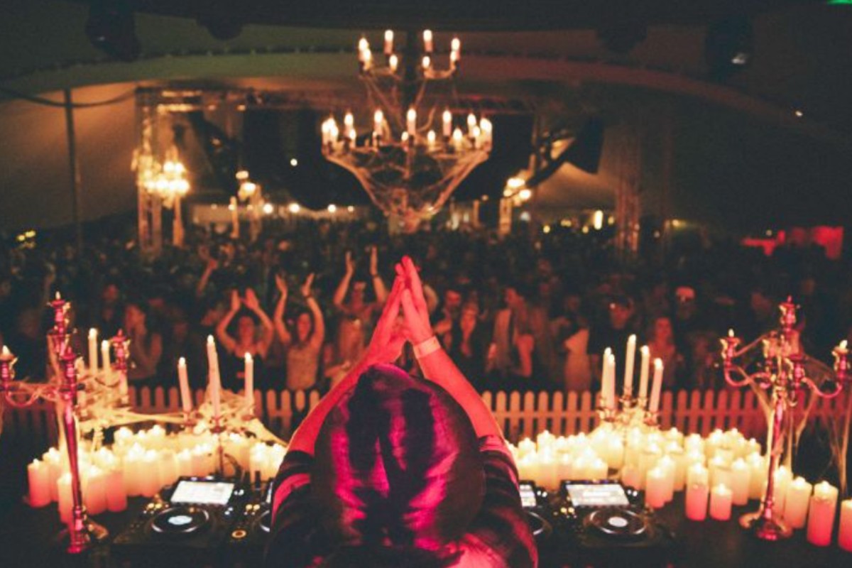 DJ playing to a crowd surrounded by candles and chandeliers